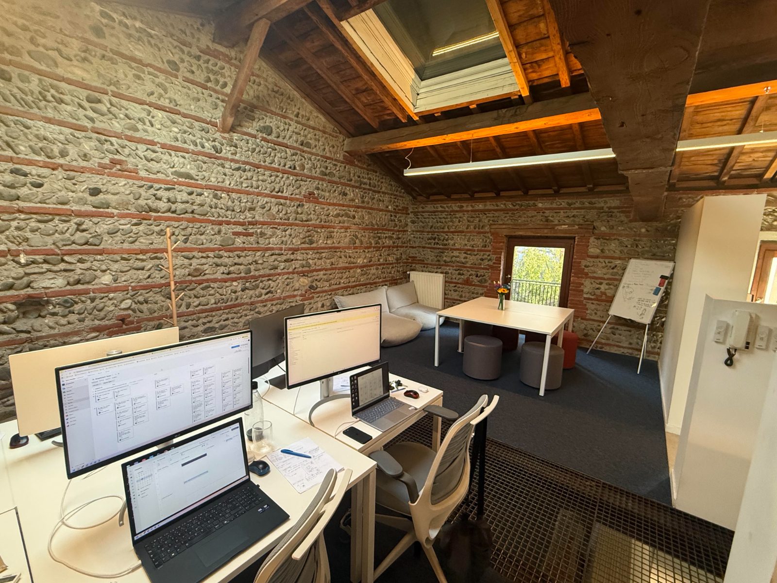 Les bureaux de Graphicient à Toulouse — plateau sous charpente, murs en galets et brique